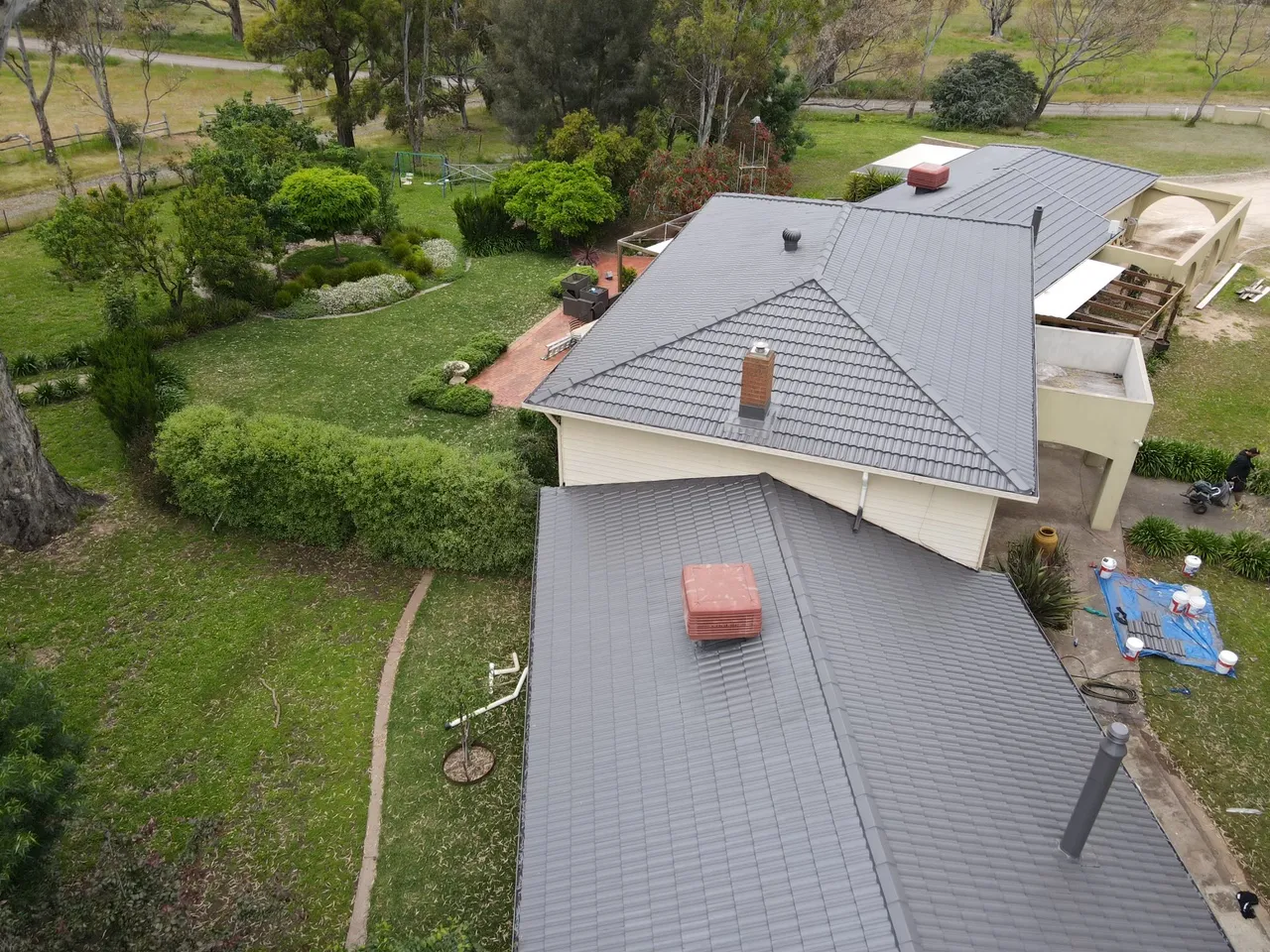 Around the chimney and cooler Recoated tile roof around a brick chimney, evaporative cooler and flue, with tidy capping at every junction, tile roof restoration by Roof Restoration Services Bendigo
