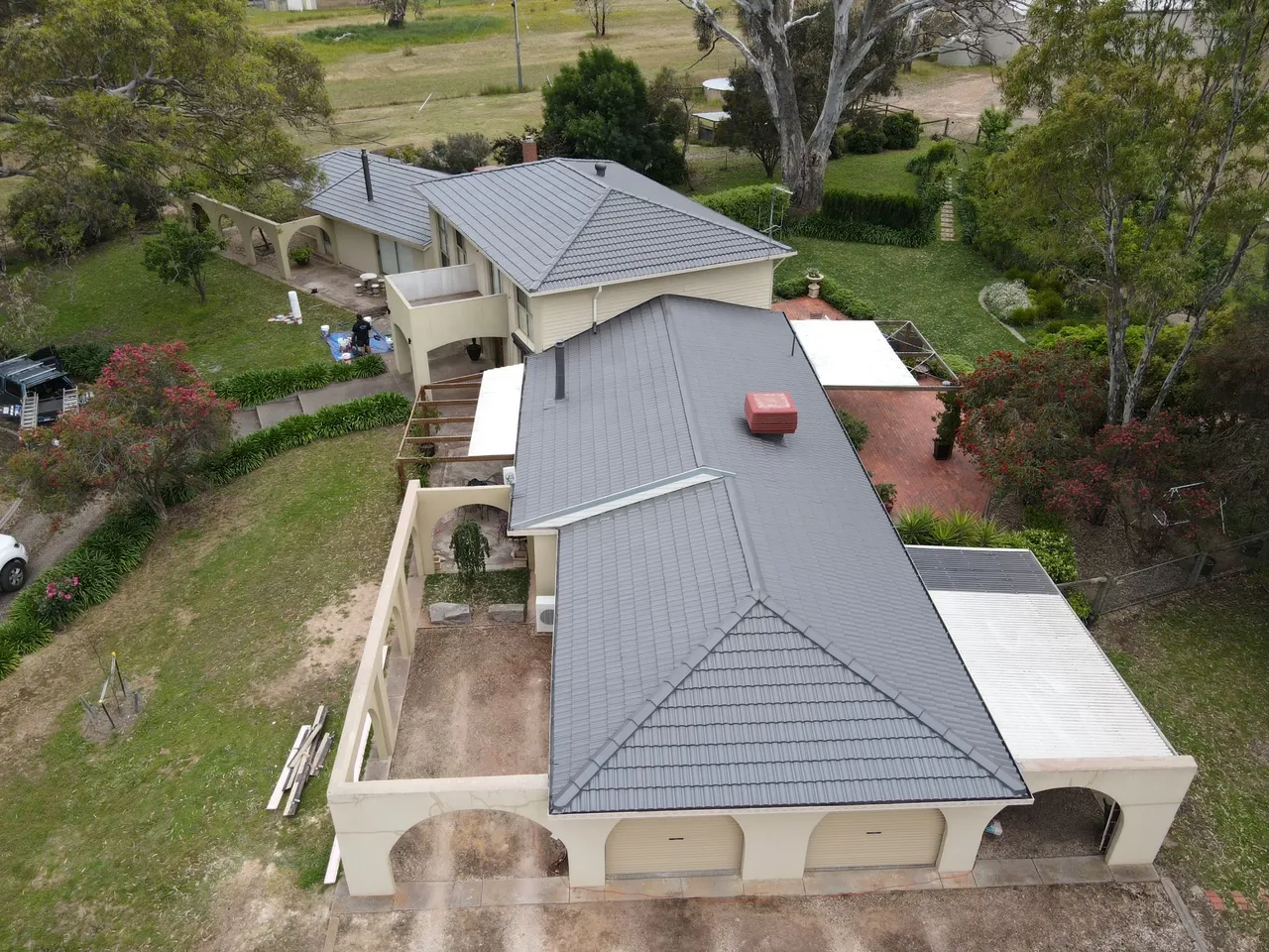 Hips, valleys and wings Restored concrete tile roof over a rendered home and arched garages, showing clean hip lines and valleys in charcoal grey, tile roof restoration by Roof Restoration Services Bendigo